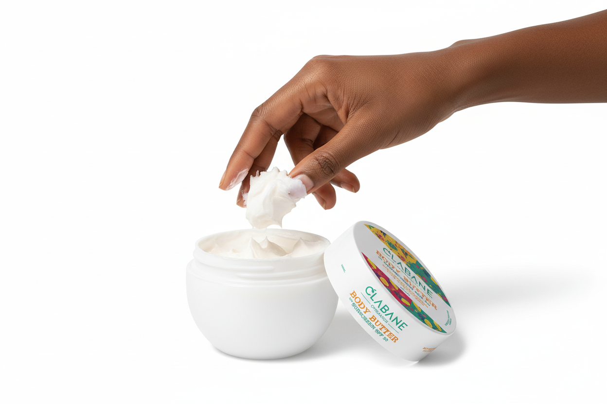 Hand scooping butter from a the Clabane Body Butter jar on a white background